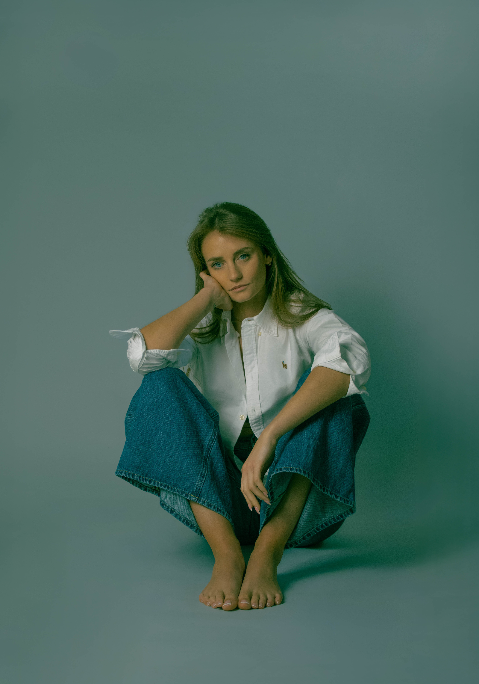 Portrait studio — femme assise en chemise blanche, fond vert